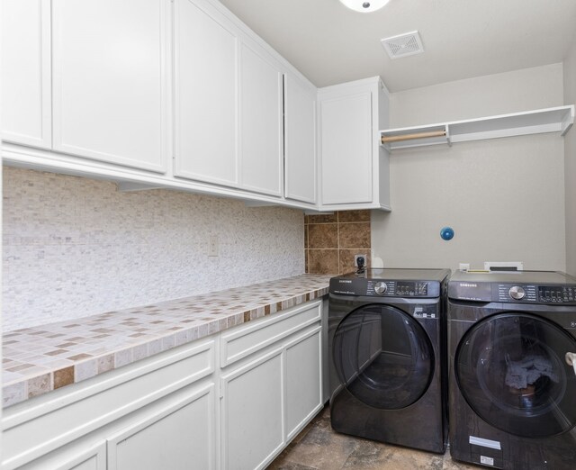 clothes washing area with cabinets and washer and dryer