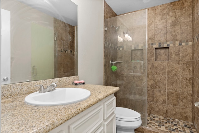 bathroom featuring a shower with door, vanity, and toilet