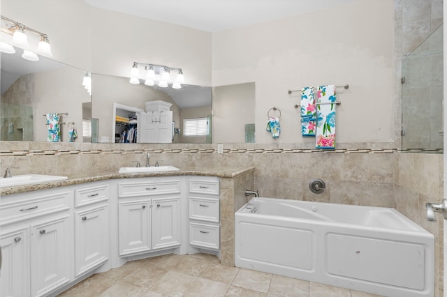 631 Apache St, Houston, TX 77022 - bathroom featuring a bath, double vanity, a tile shower, tile walls, and tile patterned floors