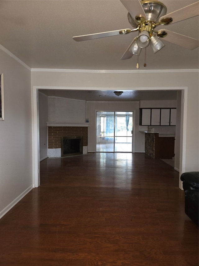 unfurnished living room with crown molding, a brick fireplace, dark hardwood / wood-style floors, and ceiling fan