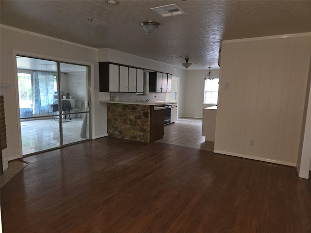 unfurnished living room featuring ornamental molding, a textured ceiling, plenty of natural light, and dark hardwood / wood-style flooring