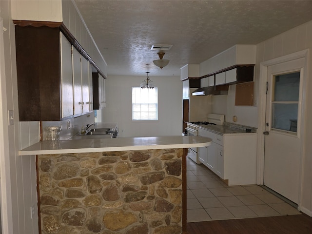 kitchen featuring kitchen peninsula, white gas stove, sink, light wood-type flooring, and white cabinetry