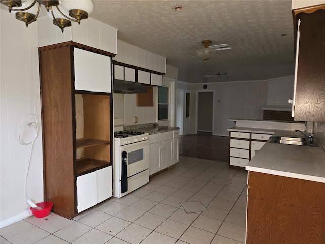 kitchen with sink, white range with gas cooktop, white cabinets, and light tile patterned floors