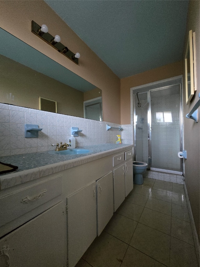 bathroom with a shower with shower door, toilet, tile patterned floors, vanity, and decorative backsplash