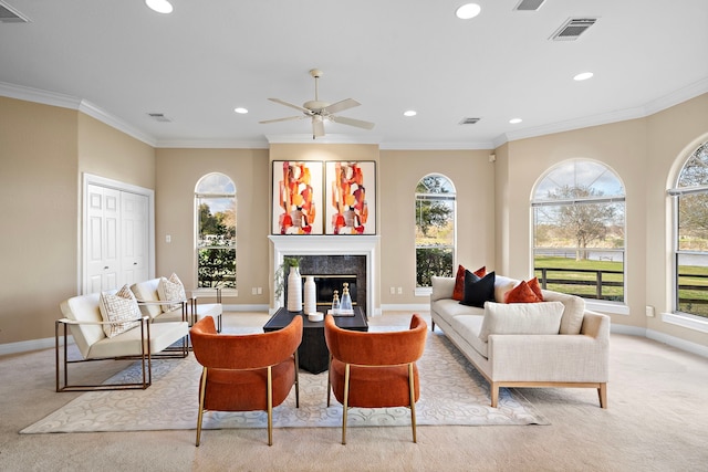 carpeted living room featuring ornamental molding and ceiling fan