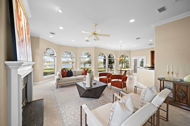 carpeted living room with a wealth of natural light, ornamental molding, and ceiling fan