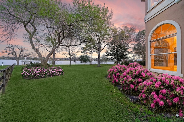 yard at dusk featuring a water view