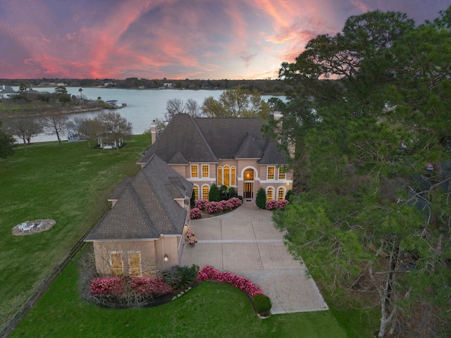 view of front of property featuring a water view, a lawn, and a garage