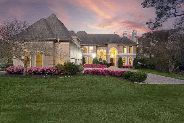 view of front of home with a garage, stone siding, a front yard, stucco siding, and a chimney