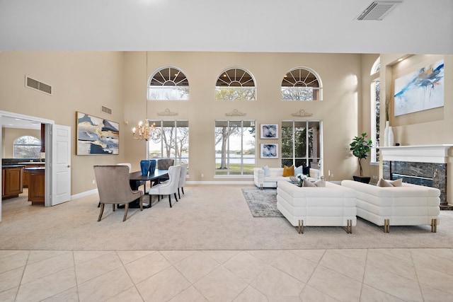 carpeted living room with a premium fireplace, a notable chandelier, and a towering ceiling