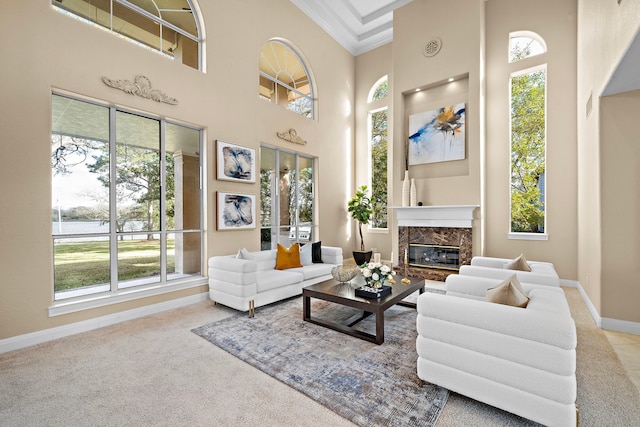 living room with crown molding, light carpet, a fireplace, and a towering ceiling