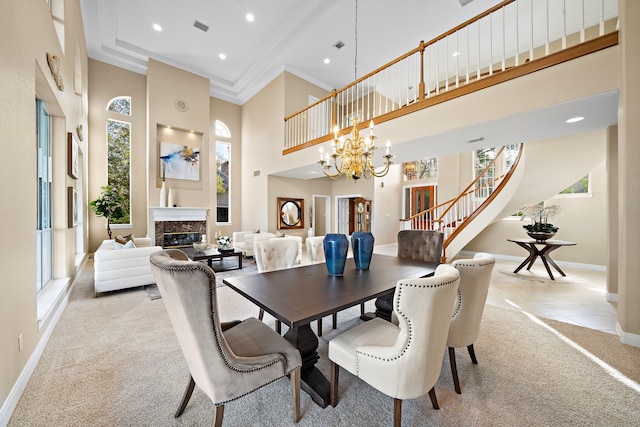 dining room featuring ornamental molding, light colored carpet, a towering ceiling, and plenty of natural light