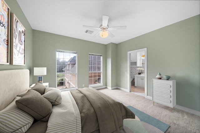 bedroom with visible vents, baseboards, ensuite bathroom, light colored carpet, and a ceiling fan