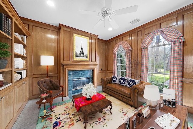 interior space with light carpet, a premium fireplace, wooden walls, and ceiling fan