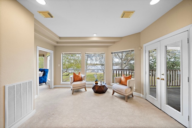 living area featuring visible vents, light carpet, and french doors