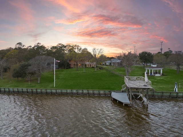 view of dock with a water view and a lawn