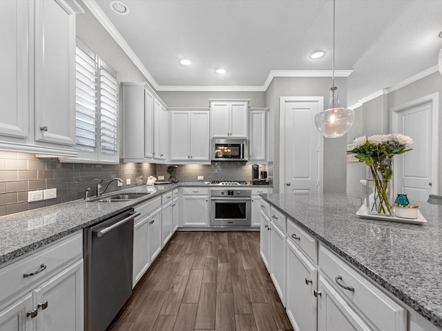 kitchen with light stone counters, sink, ornamental molding, white cabinetry, and appliances with stainless steel finishes