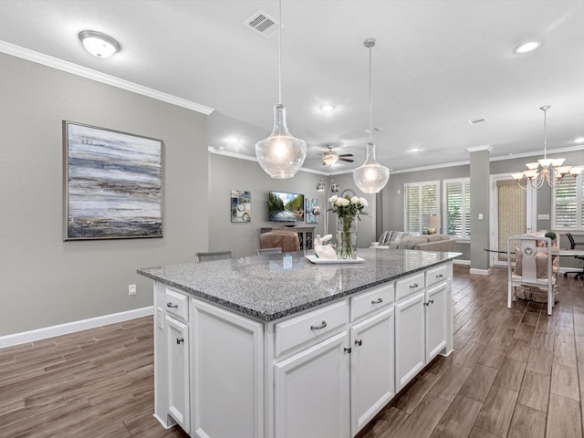 kitchen with dark stone counters, a kitchen island, white cabinetry, dark hardwood / wood-style floors, and pendant lighting