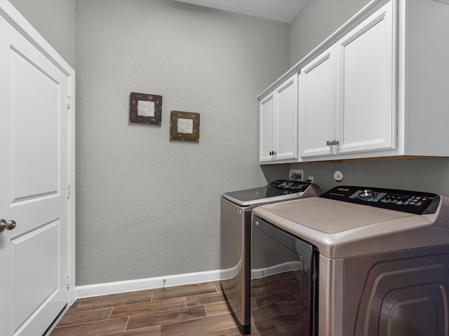 clothes washing area with cabinets, dark hardwood / wood-style flooring, and washer and clothes dryer