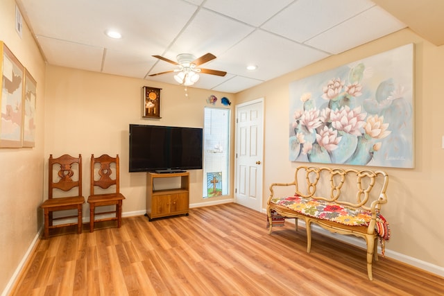 sitting room featuring a drop ceiling, wood-type flooring, and ceiling fan