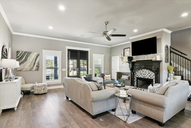 living room with crown molding, a stone fireplace, hardwood / wood-style flooring, and ceiling fan