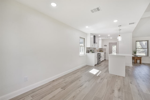 kitchen featuring white cabinetry, light wood-type flooring, decorative light fixtures, and plenty of natural light