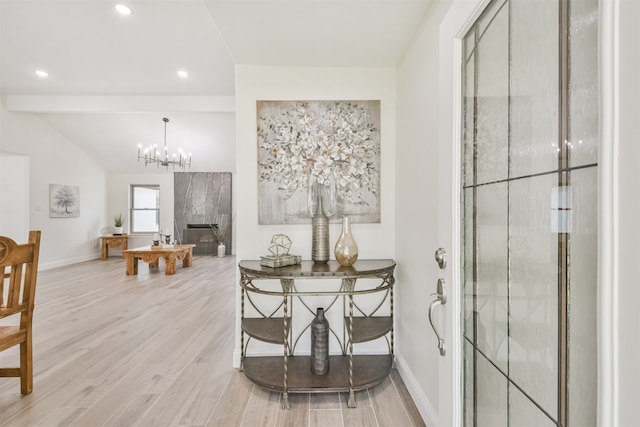 dining area featuring an inviting chandelier, lofted ceiling, a fireplace, and light hardwood / wood-style floors