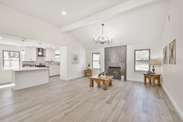 living room featuring beamed ceiling, light hardwood / wood-style flooring, an inviting chandelier, a fireplace, and high vaulted ceiling