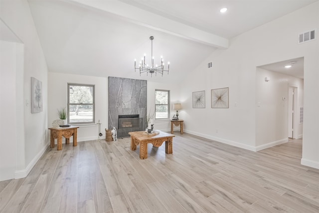 living room with light hardwood / wood-style floors, a healthy amount of sunlight, beamed ceiling, and a fireplace