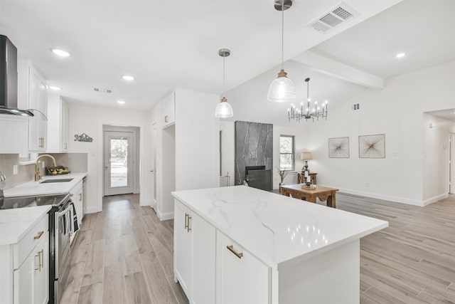 kitchen featuring stainless steel range with electric cooktop, a kitchen island, a premium fireplace, white cabinetry, and vaulted ceiling with beams