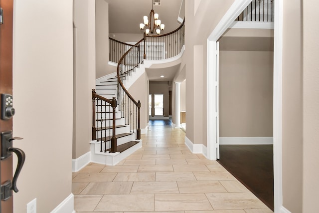 tiled foyer entrance featuring a towering ceiling and a chandelier