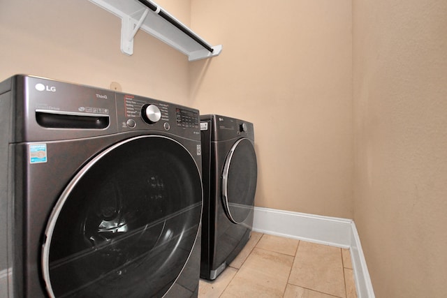 laundry room featuring washer and clothes dryer and light tile patterned floors