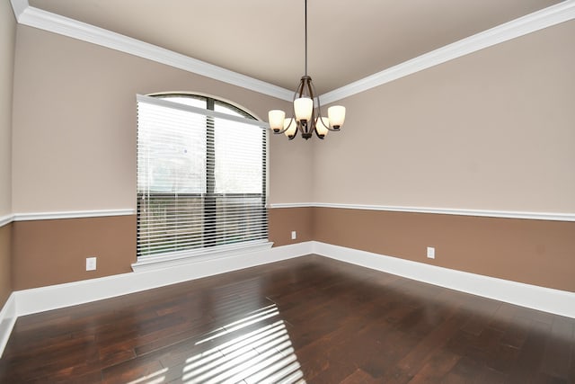 spare room featuring wood-type flooring, ornamental molding, and a chandelier