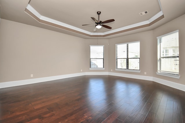 spare room featuring a raised ceiling, ornamental molding, and dark hardwood / wood-style flooring