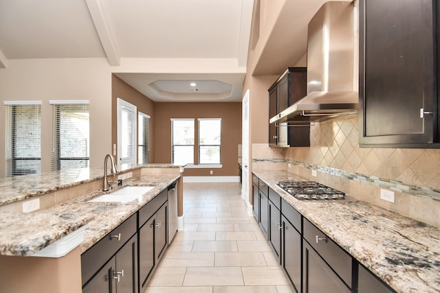 kitchen featuring wall chimney range hood, appliances with stainless steel finishes, sink, plenty of natural light, and light stone counters