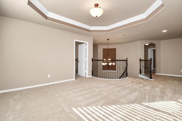 carpeted empty room featuring crown molding and a raised ceiling