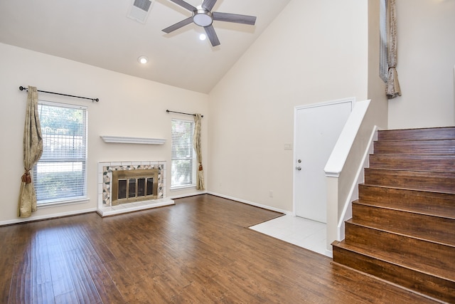 unfurnished living room with high vaulted ceiling, hardwood / wood-style flooring, plenty of natural light, and a tile fireplace