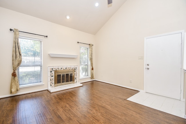 unfurnished living room with a healthy amount of sunlight, hardwood / wood-style flooring, and high vaulted ceiling