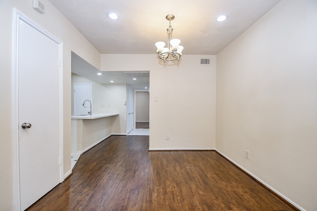 unfurnished room with a notable chandelier, sink, and dark wood-type flooring