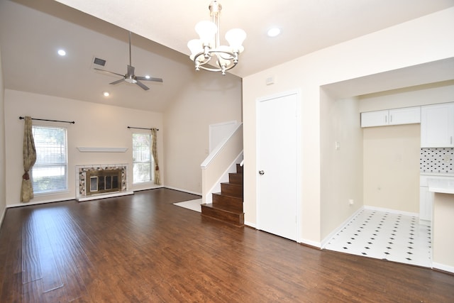 unfurnished living room with lofted ceiling, ceiling fan with notable chandelier, and dark hardwood / wood-style flooring