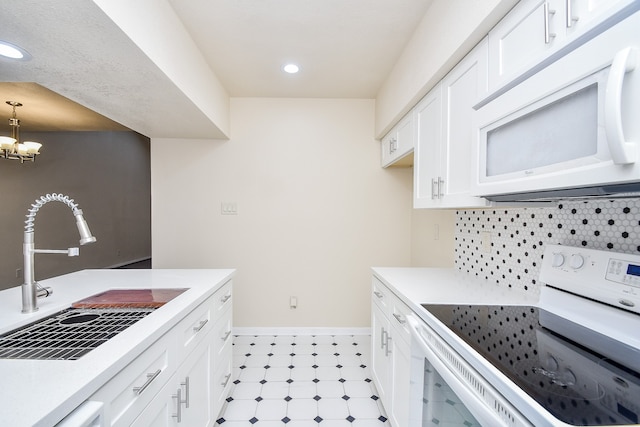 kitchen with tasteful backsplash, sink, electric stove, pendant lighting, and white cabinets