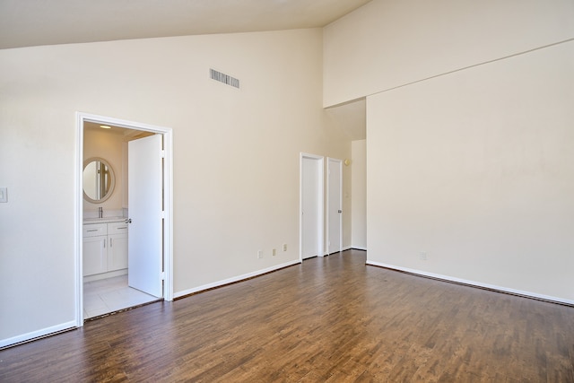 spare room with high vaulted ceiling and light wood-type flooring