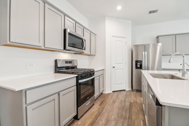 kitchen featuring gray cabinets, stainless steel appliances, light hardwood / wood-style flooring, and sink