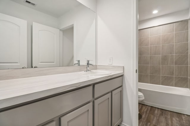 full bathroom featuring vanity, toilet, wood-type flooring, and tiled shower / bath