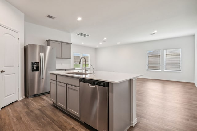 kitchen featuring appliances with stainless steel finishes, an island with sink, gray cabinets, and sink