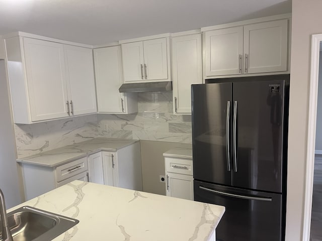 kitchen with light stone countertops, white cabinetry, tasteful backsplash, and stainless steel refrigerator