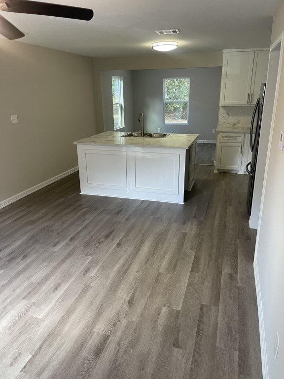 kitchen featuring fridge, a center island with sink, sink, white cabinetry, and dark hardwood / wood-style flooring