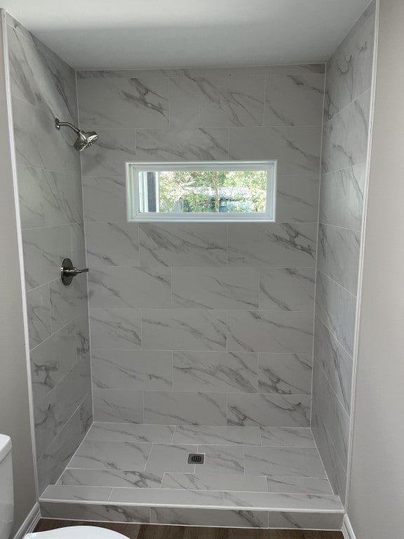 bathroom with a tile shower and toilet