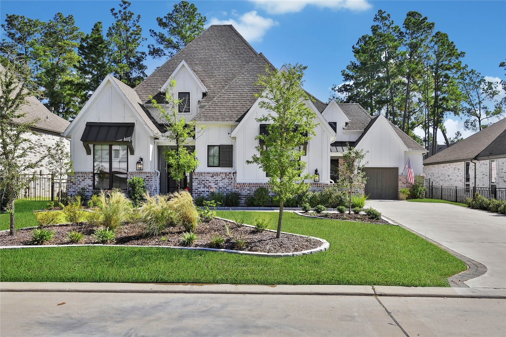 modern farmhouse featuring board and batten siding, brick siding, a standing seam roof, and fence