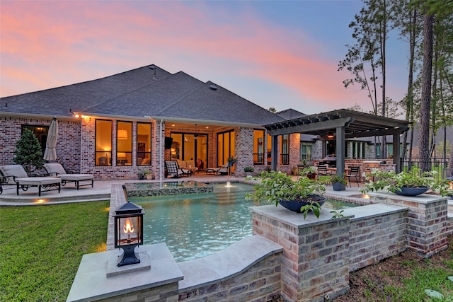 pool at dusk featuring a yard, ceiling fan, a patio area, and a pergola